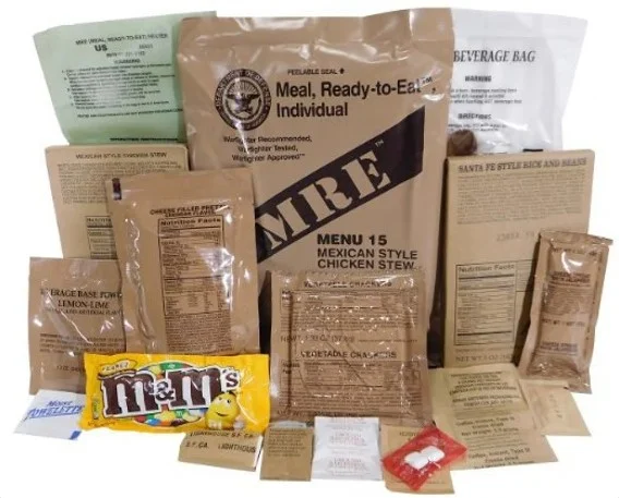 Ensemble de sachets et paquetages alimentaires militaires et de survie, plats MRE emballés, snacks M&M’s en arrière-plan.