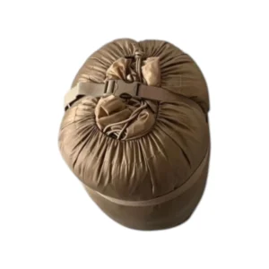 Sac de couchage compressé prêt pour le bivouac en montagne autorisé, avec sangle de fermeture et isolation compacte.